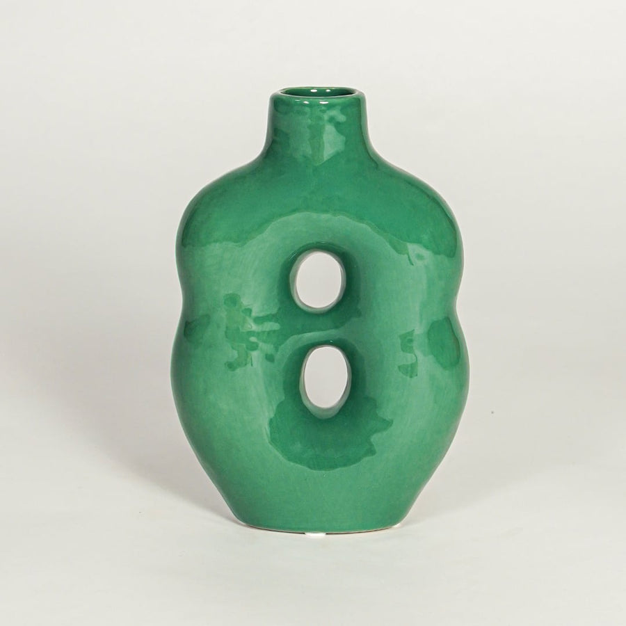 Modern green ceramic decorative vase with sculptural form and glossy glaze isolated on white background.