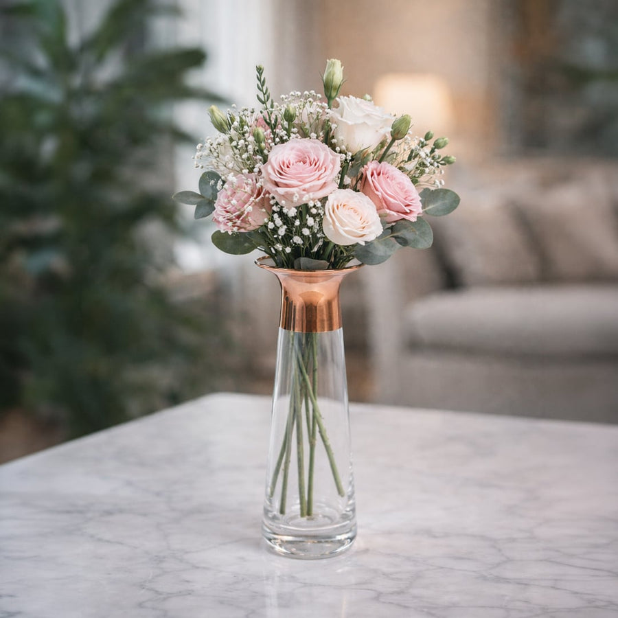 Clear glass decorative vase styled with pink flowers on a table for elegant contemporary home decor settings.