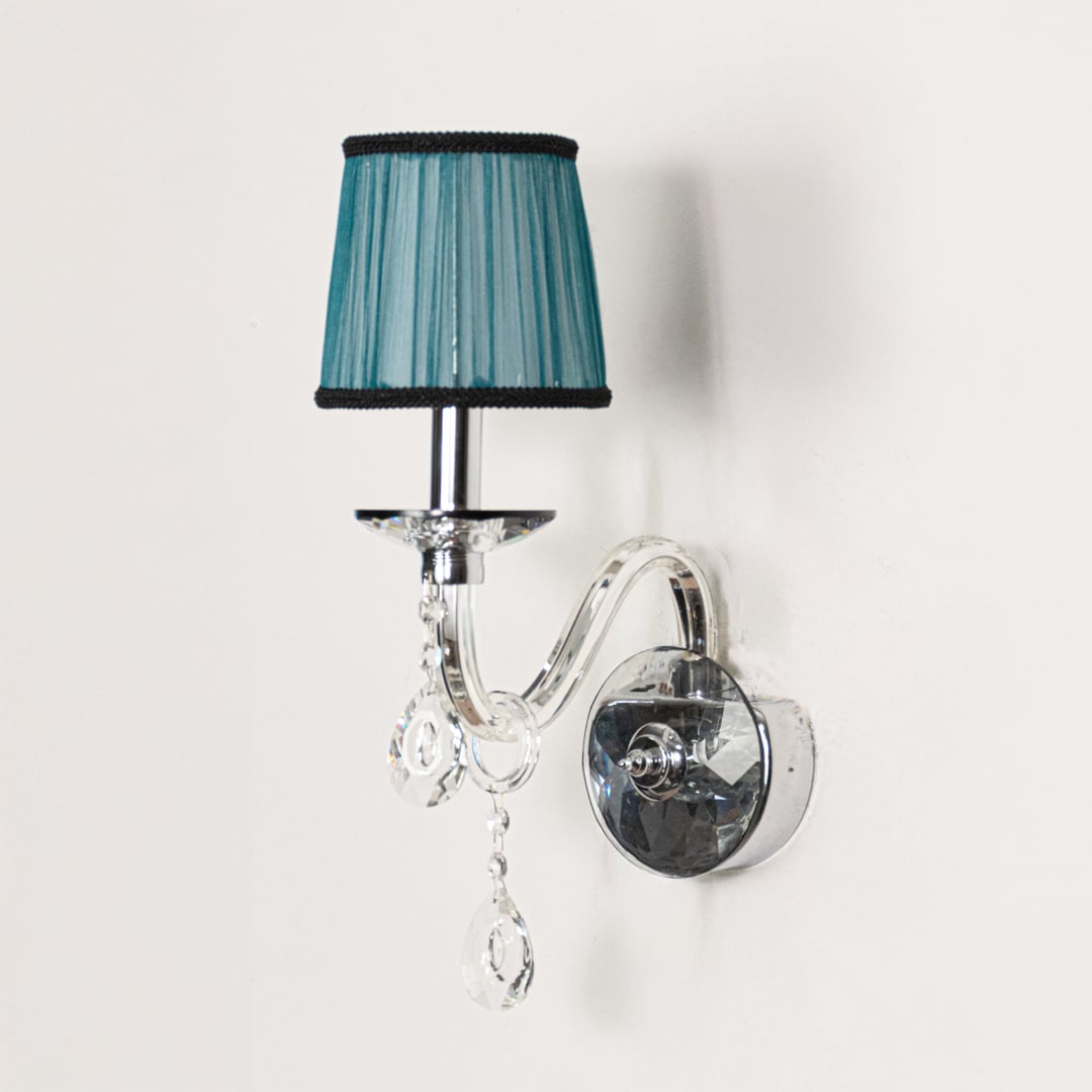 Wall light with chrome base and blue fabric shade turned off with crystal drops on white background.