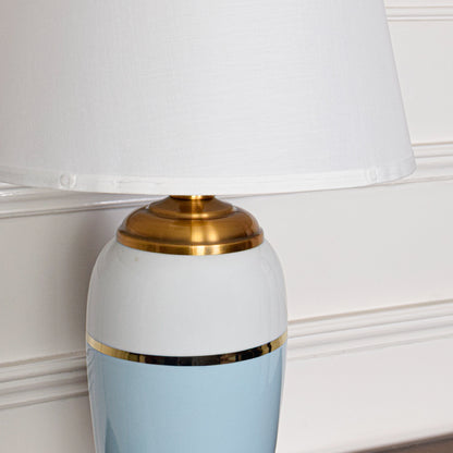 Close up table lamp with white and blue ceramic base and gold accent with fabric shade classic decorative lighting for home decor.