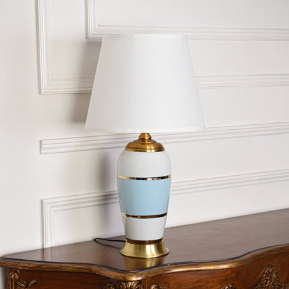 Decorative table lamp with white and blue ceramic base and white shade on wooden table ideal for bedroom and living room decor.