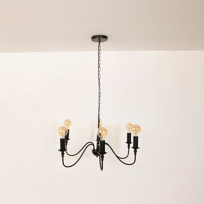 Detailed closeup of amber Edison globe bulb with black metal candle holder socket on vintage style chandelier curved arms.