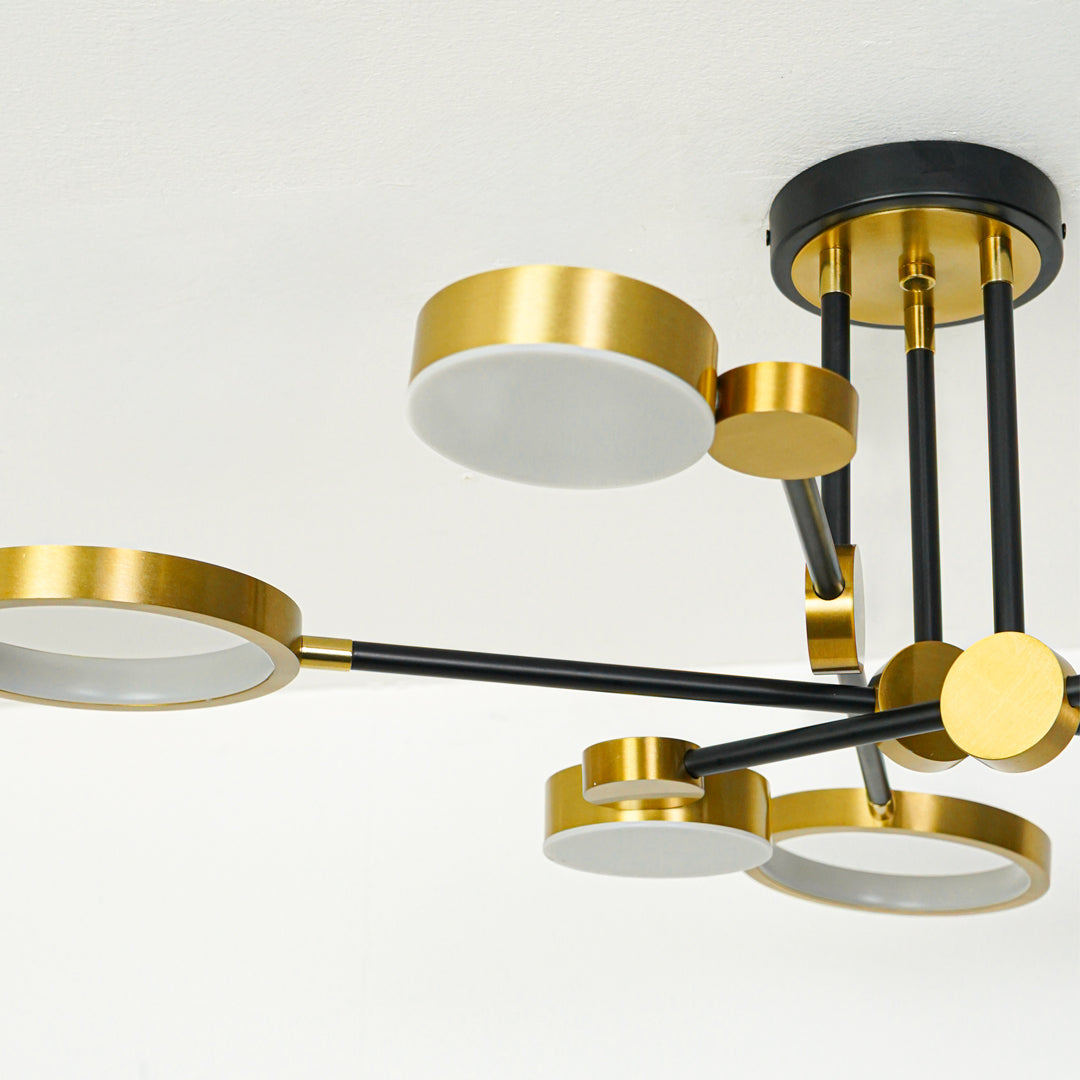 Stylish modern chandelier with black and gold metal frame and circular ring elements suspended against clean ceiling background for luxury decor.