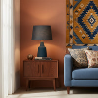 Modern table lamp with grey fabric shade and smooth blue base adding warm ambient lighting that enhances stylish contemporary interior home decor settings.