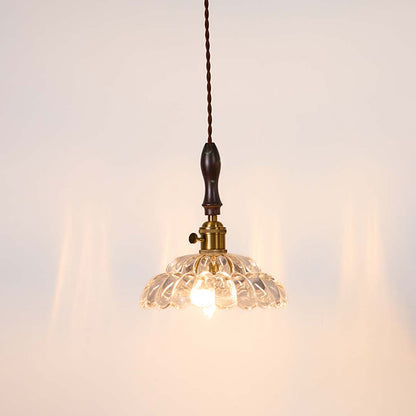Textured clear glass and brass metal pendant light with warm glow for stylish home interiors.