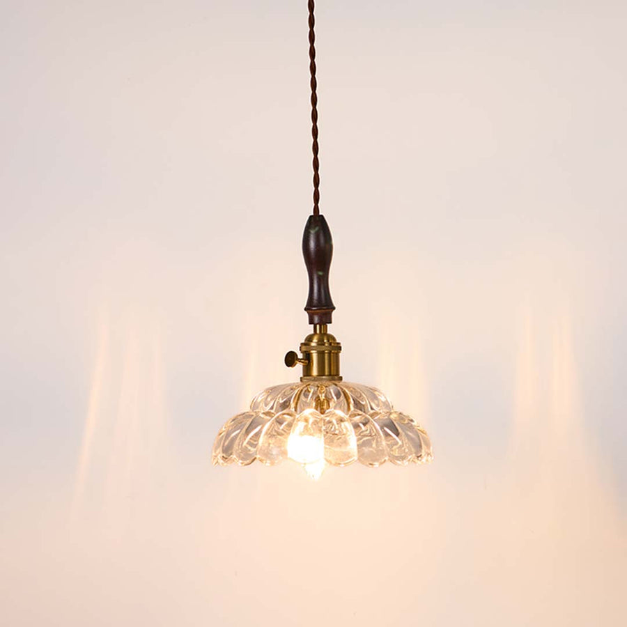 Textured clear glass and brass metal pendant light with warm glow for stylish home interiors.