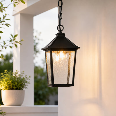 Black metal and glass outdoor hanging light for porch entrance balcony and covered patio with warm ambient lighting.
