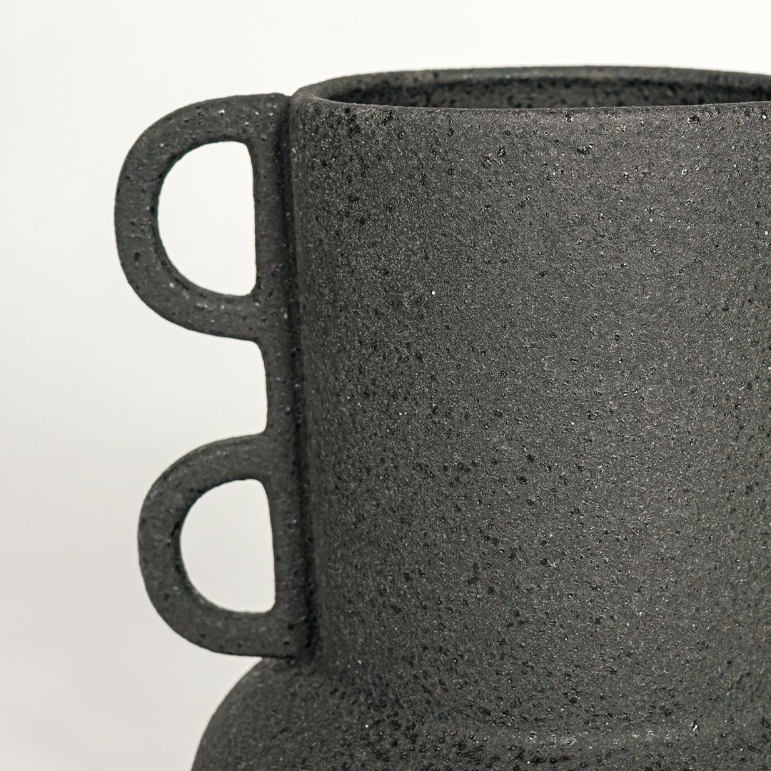 Close view of black textured ceramic vase with loop side handles highlighting matte finish for table shelf or console placement.