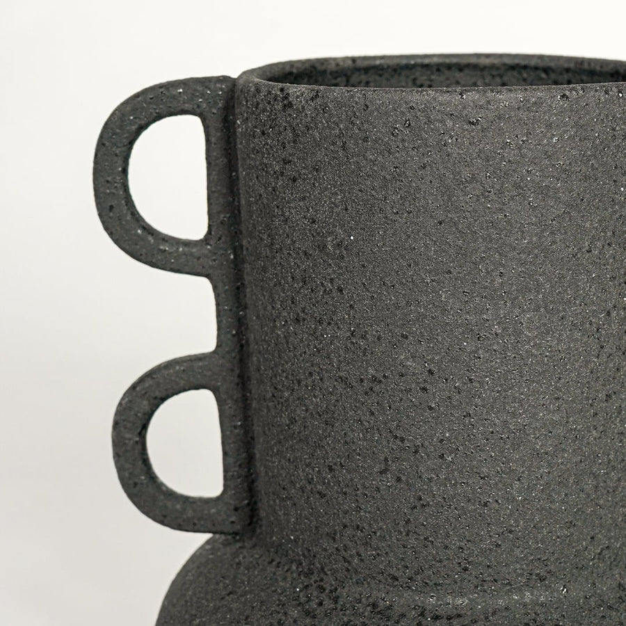 Close view of black textured ceramic vase with loop side handles highlighting matte finish for table shelf or console placement.