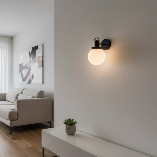 Modern black metal wall light with frosted glass globe for stylish living room and bedroom decor spaces.