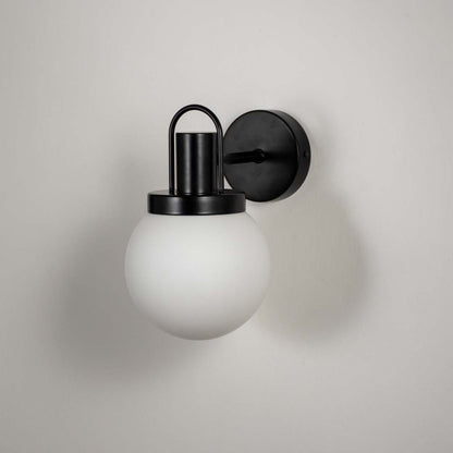 Closeup of black metal wall light with white frosted glass shade for modern hallway and luxury decor spaces.