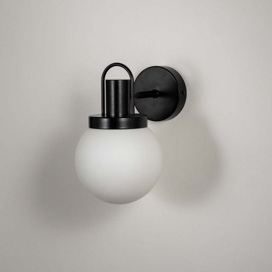 Closeup of black metal wall light with white frosted glass shade for modern hallway and luxury decor spaces.
