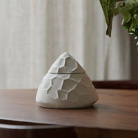 White ceramic decorative vase with geometric textured design placed on wooden table for modern home decor styling.