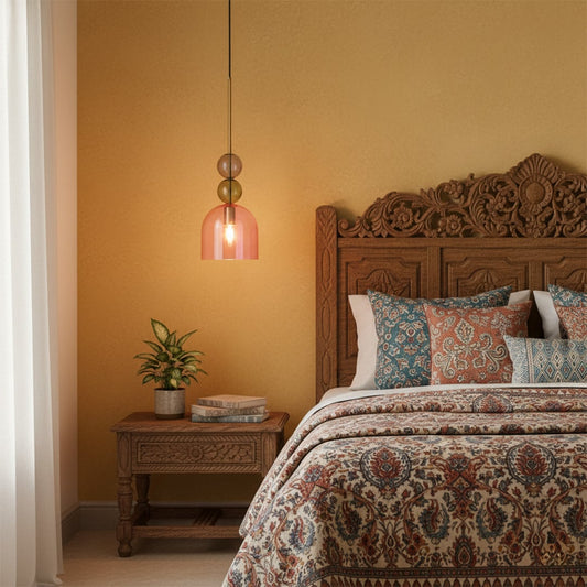 Pendant light with glass shade in warm pink tone hanging beside bed adding soft ambient lighting and cozy elegance to bedroom decor.
