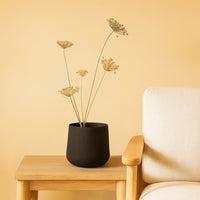 Black textured metal planter styled in a warm minimal scene adding bold modern elegance to contemporary home decor.