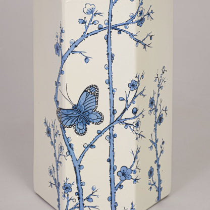 Closeup of cream ceramic vase showcasing detailed blue floral branches butterfly motif and smooth glazed finish.
