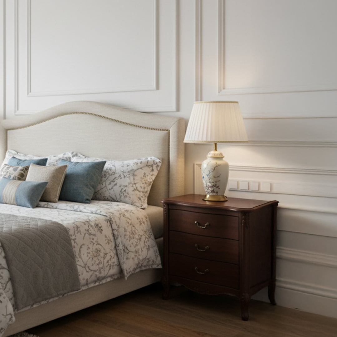 Off white ceramic table lamp with white pleated shade placed on bedside table adding charm to luxury interiors.