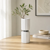 White ceramic flower vase with green stems placed on wooden table for elegant modern home decor styling.