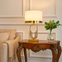 White fabric lamp on carved console table with light on and beige sofa background for classic warm décor.