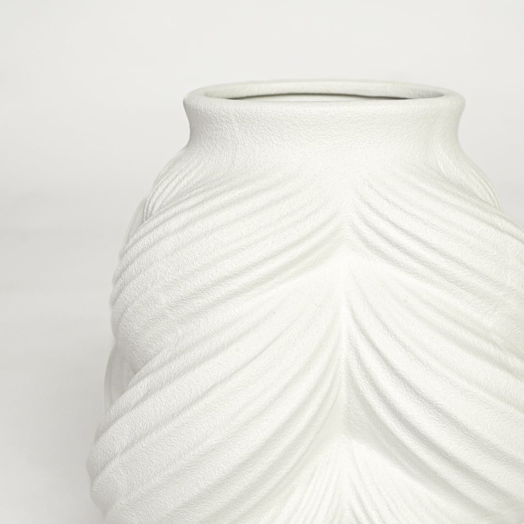 Close view of white ceramic sculpted vase highlighting layered leaf pattern and smooth matte finish.