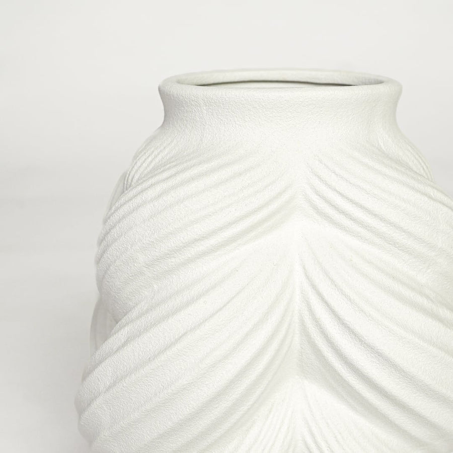 Close view of white ceramic sculpted vase highlighting layered leaf pattern and smooth matte finish.