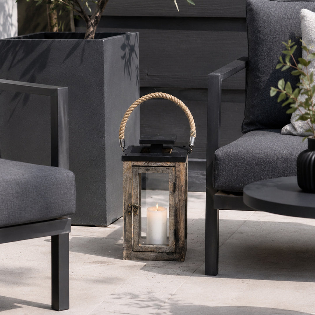 Decorative lantern with a candle on a patio with chairs and plants.