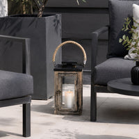 Decorative lantern with a candle on a patio with chairs and plants.