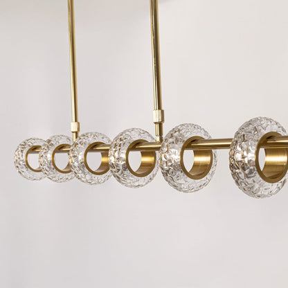 Closeup of golden metal chandelier featuring clear glass ring lights and sleek rod design for luxury modern interior decor.