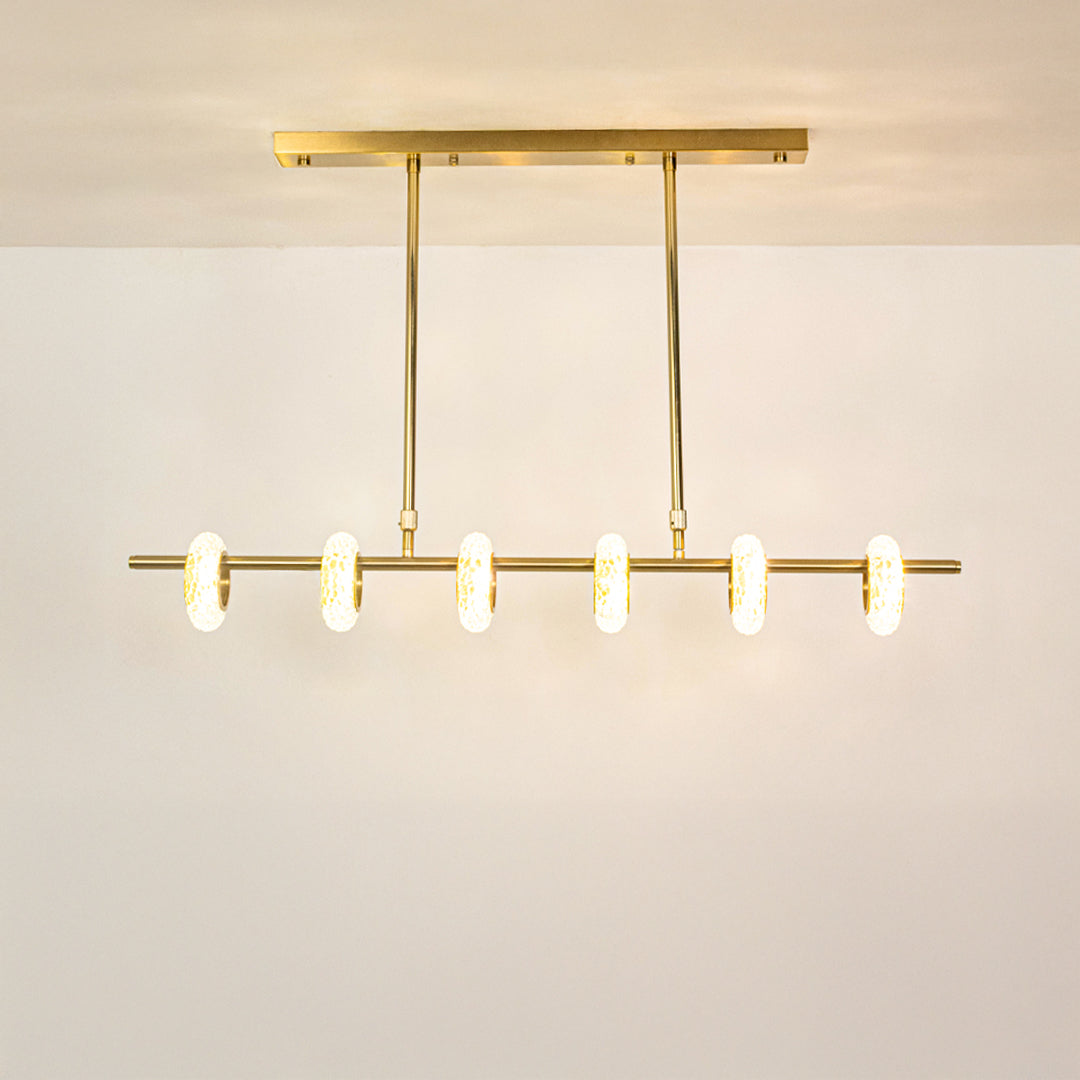 Gold metal linear chandelier with illuminated tube shades creating elegant ambient lighting for modern dining spaces.