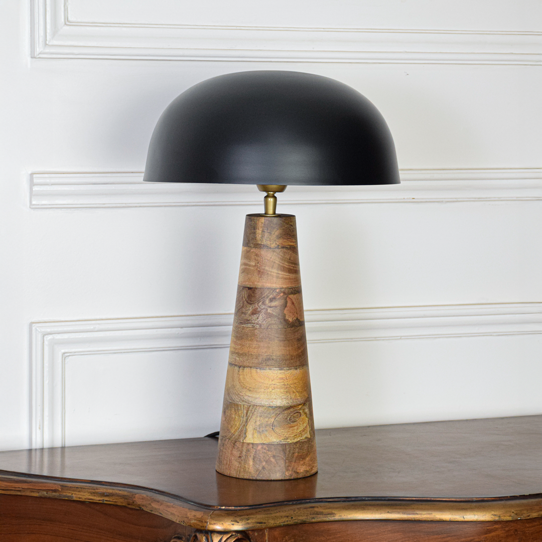 Table lamp table light off on white background featuring black dome shade with sculpted wooden base for minimalist product display.