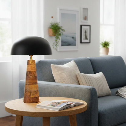 Table lamp styled on round wooden side table beside blue sofa with black dome shade and natural wood base creating soft modern living room Decor.