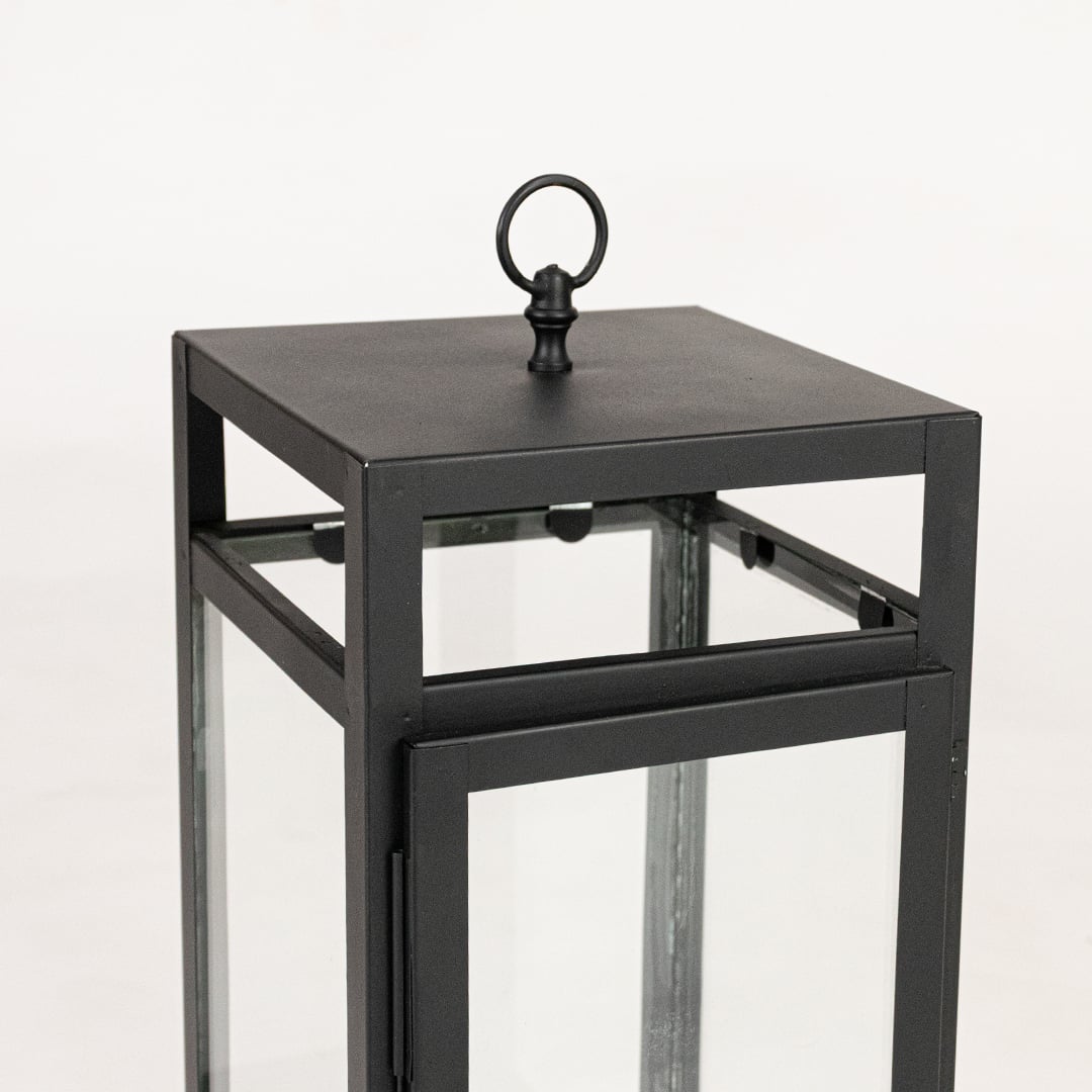 Closeup of black metal lantern showing square frame clean lines glass panels and modern minimalist decorative finish.
