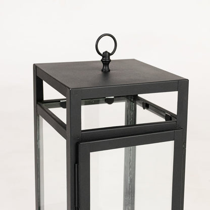 Closeup of black metal lantern showing square frame clean lines glass panels and modern minimalist decorative finish.