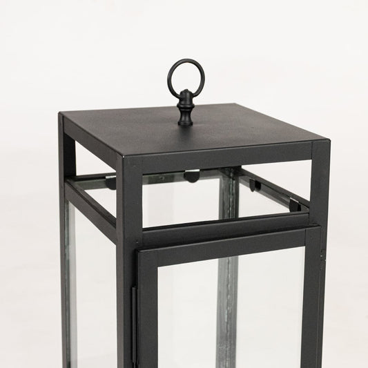 Closeup of black metal lantern showing square frame clean lines glass panels and modern minimalist decorative finish.