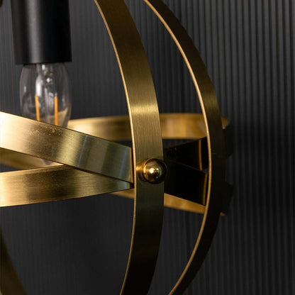A closeup view of a spherical pendant light showing layered metal bands and central bulb holder capturing warm metallic tones and detailed craftsmanship.