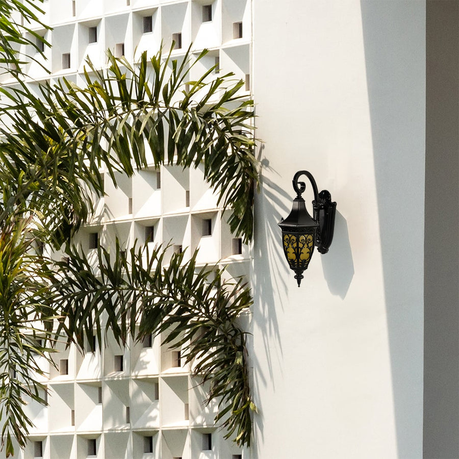 Decorative outdoor lantern mounted on a wall showing elegant curves and warm illuminated glass.