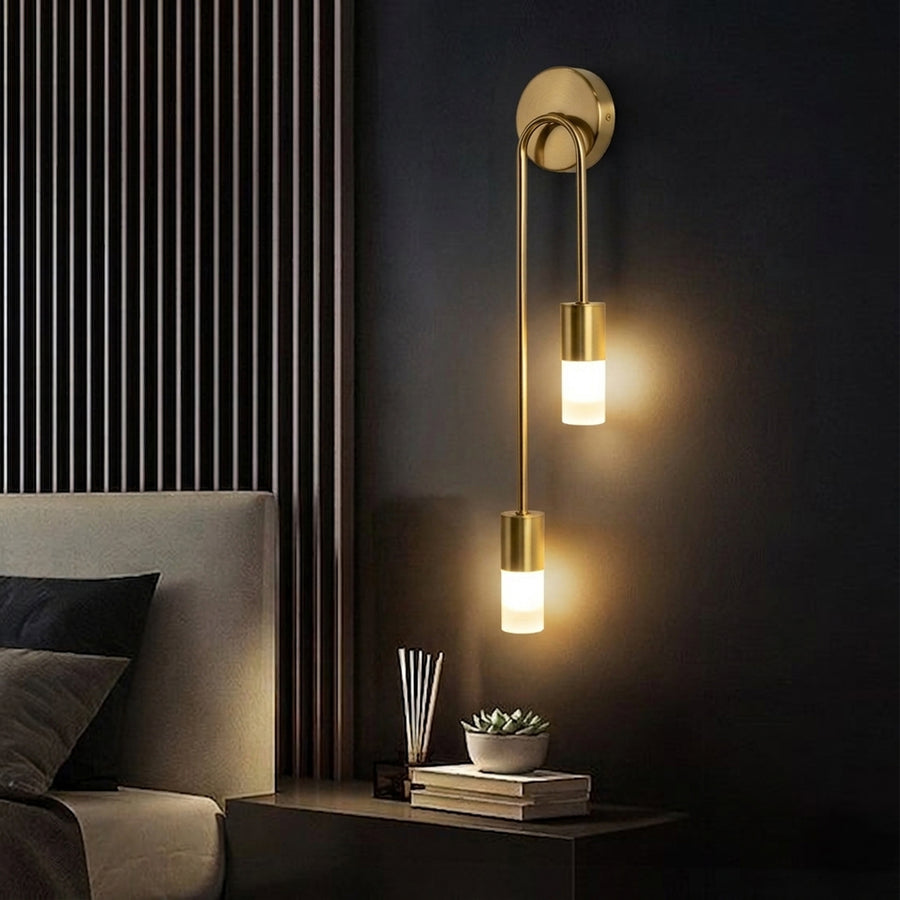 Elegant gold metal wall light glowing beside bed for luxury bedroom interior decor and ambient lighting styling.