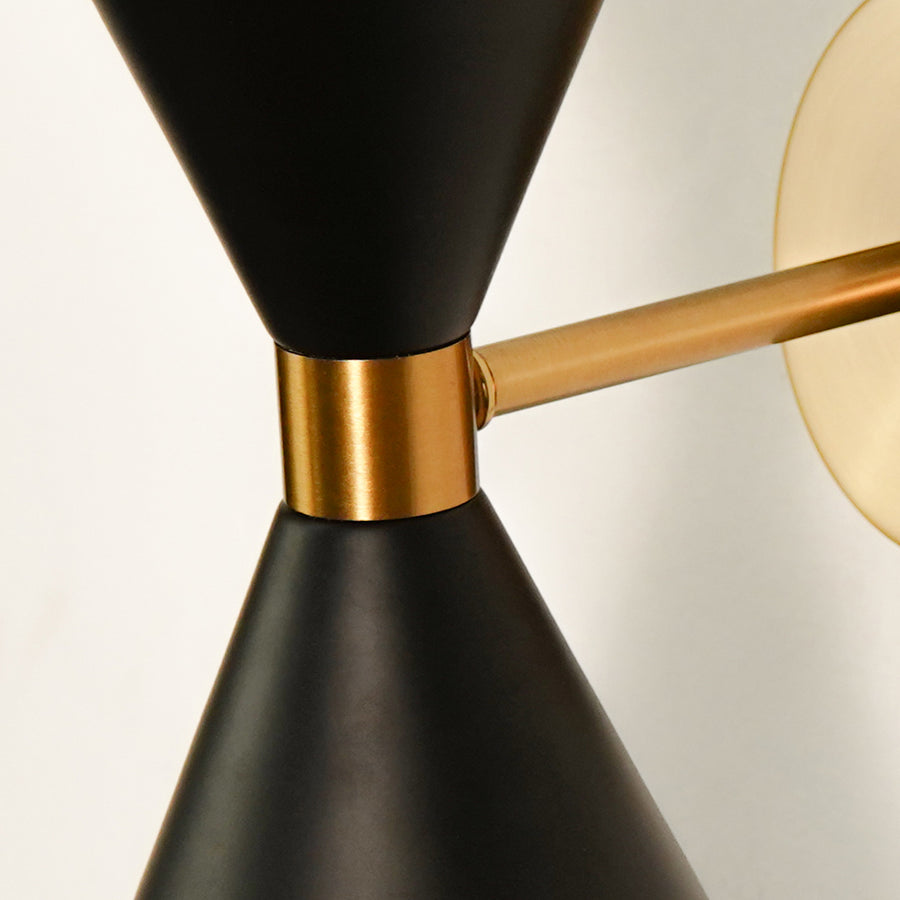 Detailed close up view of a modern black and gold brass hourglass wall sconce highlighting the sleek metal joint connection.