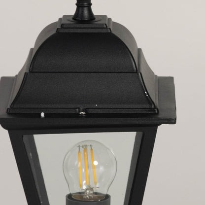 Closeup of black pillar lamp with glass shade and bulb showcasing elegant design for outdoor home garden and gate lighting.