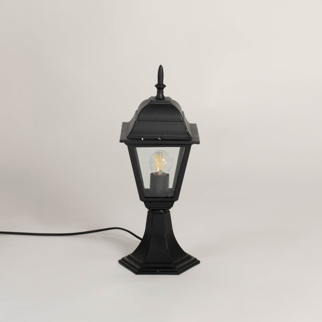 Classic black pillar lamp with clear glass panels shown with light off on white background for outdoor garden lighting.