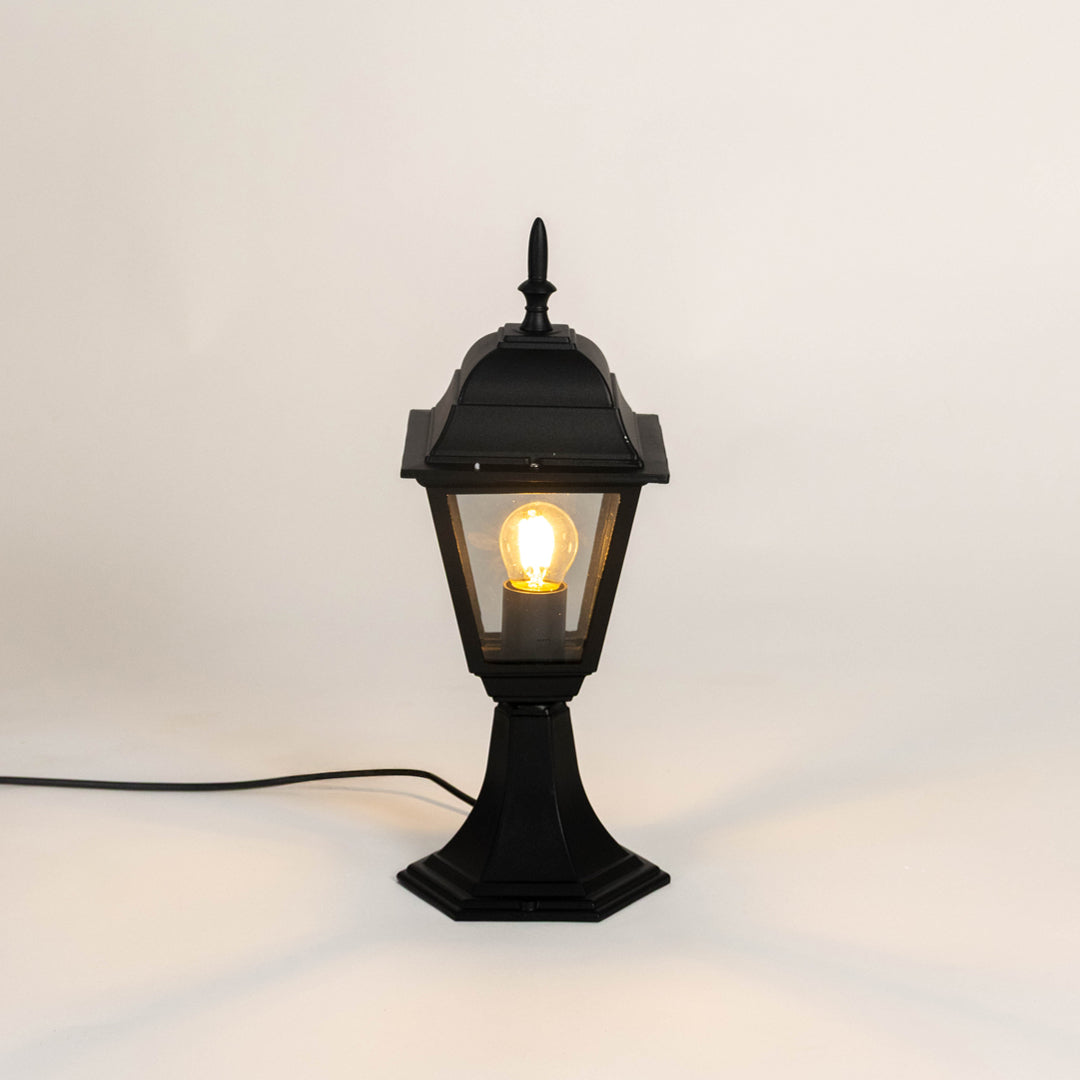 Classic black metal gate light with warm glowing bulb for modern outdoor decor styling use.