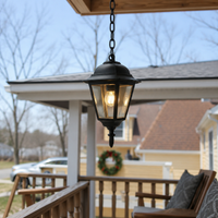 Classic black aluminum chain hanging tapered glass lantern pendant light from wooden porch roof for backyard patio decor.