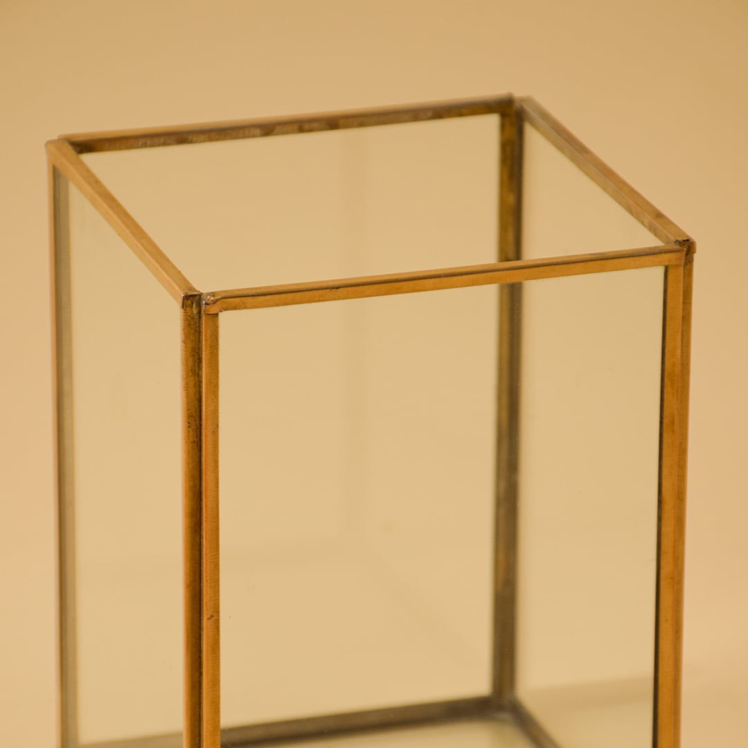 Detailed view of elegant rectangular brass frame on glass vase for luxury modern home decor and sophisticated shelf display.