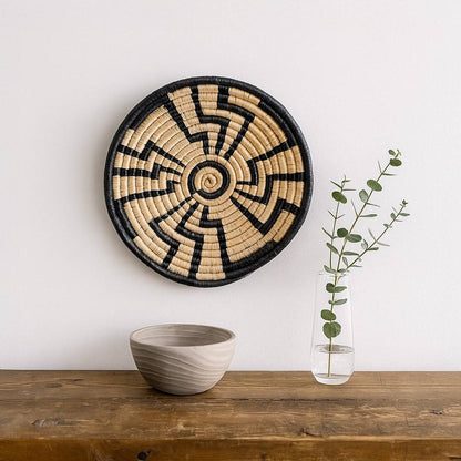 Handwoven seagrass wall basket decor in natural beige and black displayed on a shelf creating elegant boho home styling.