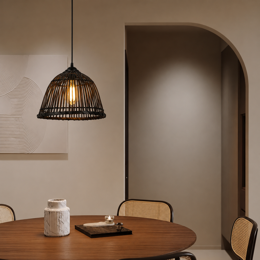 A black woven cage pendant light hangs over a round wooden dining table in a modern, warm-toned dining room with woven-back chairs and a beige arched hallway in the background.