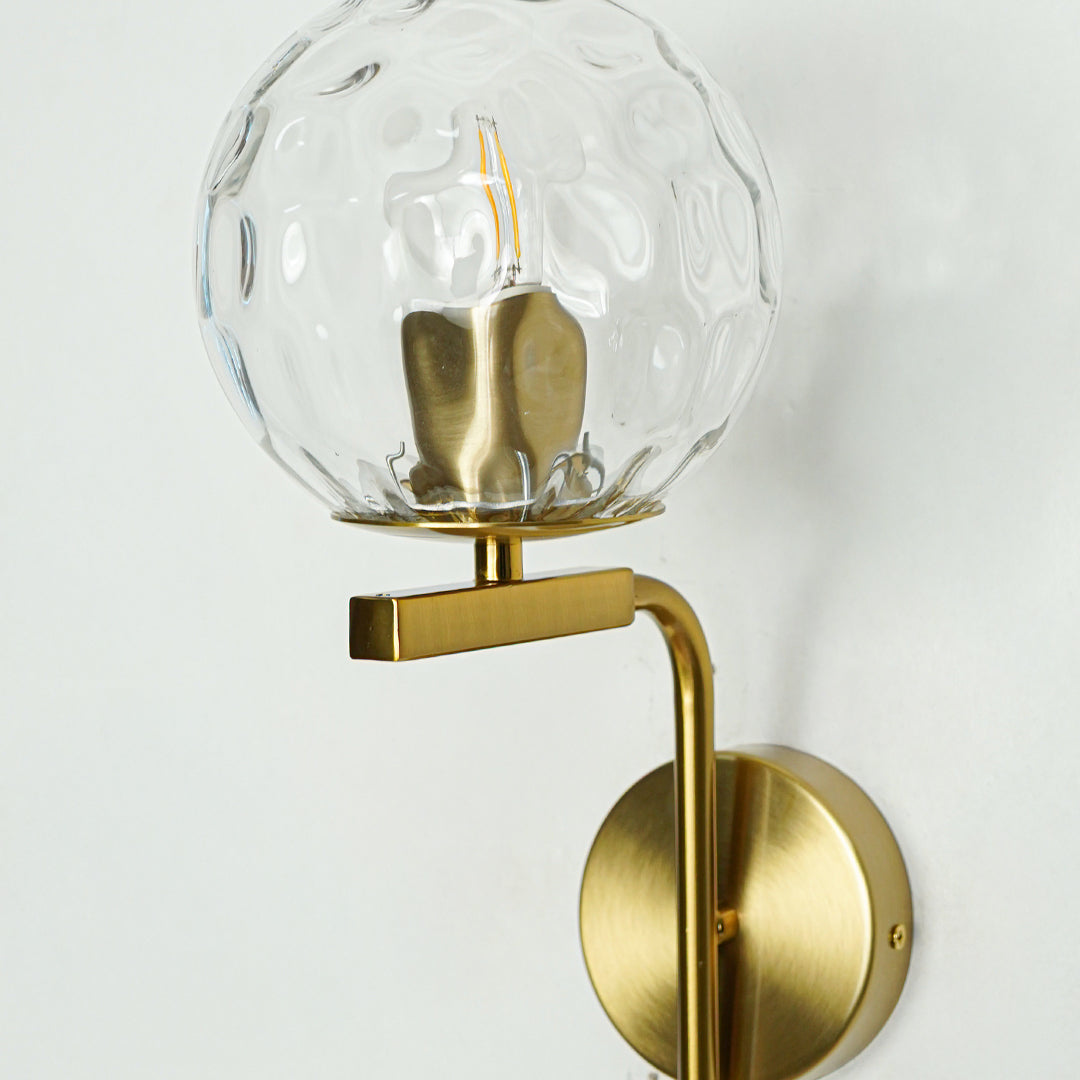Closeup of textured glass and gold metal wall light for elegant hallway and luxury decor styling spaces.