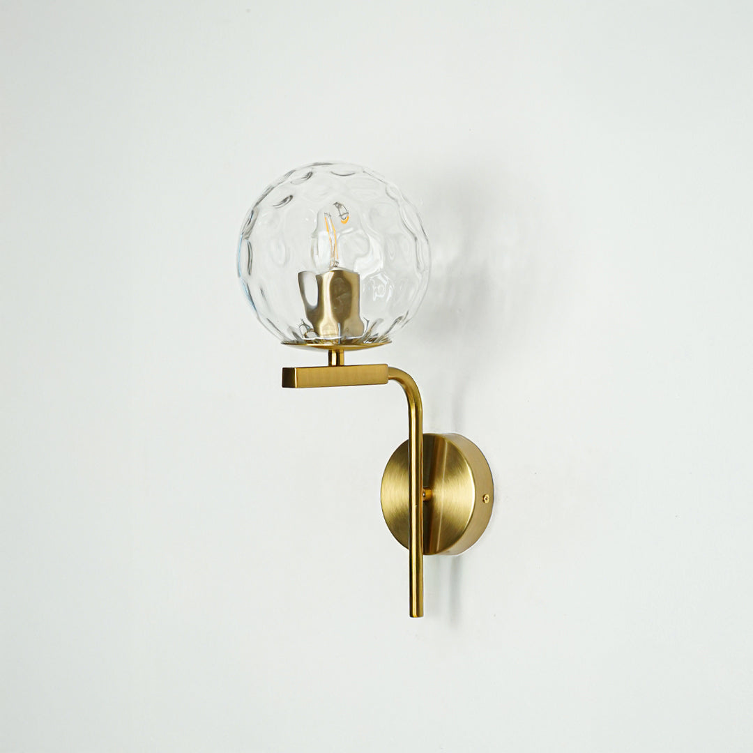 Modern gold metal wall light with crystal glass globe for contemporary bedroom and luxury decor spaces.

