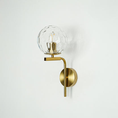 Modern gold metal wall light with crystal glass globe for contemporary bedroom and luxury decor spaces.

