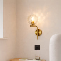 Modern gold metal wall light with textured glass globe for elegant bedroom and luxury decor styling spaces.