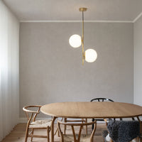 Modern dining space with dual white globe pendant lights above wooden table minimal elegant lighting for contemporary interiors.